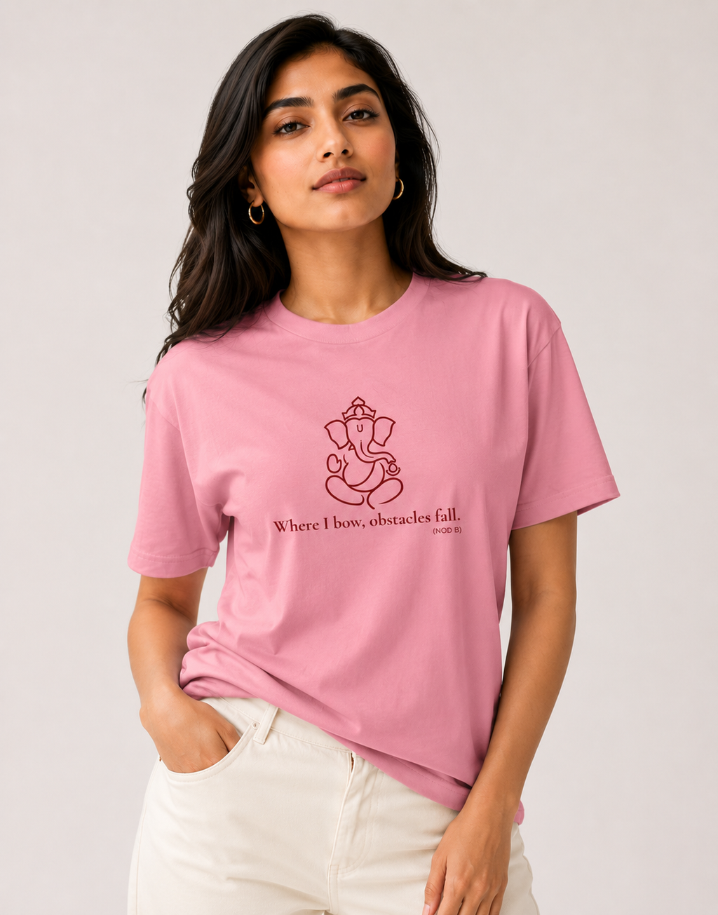 Woman modeling a baby pink unisex cotton t-shirt with a red Lord Ganapati design by Vedic Bridge.