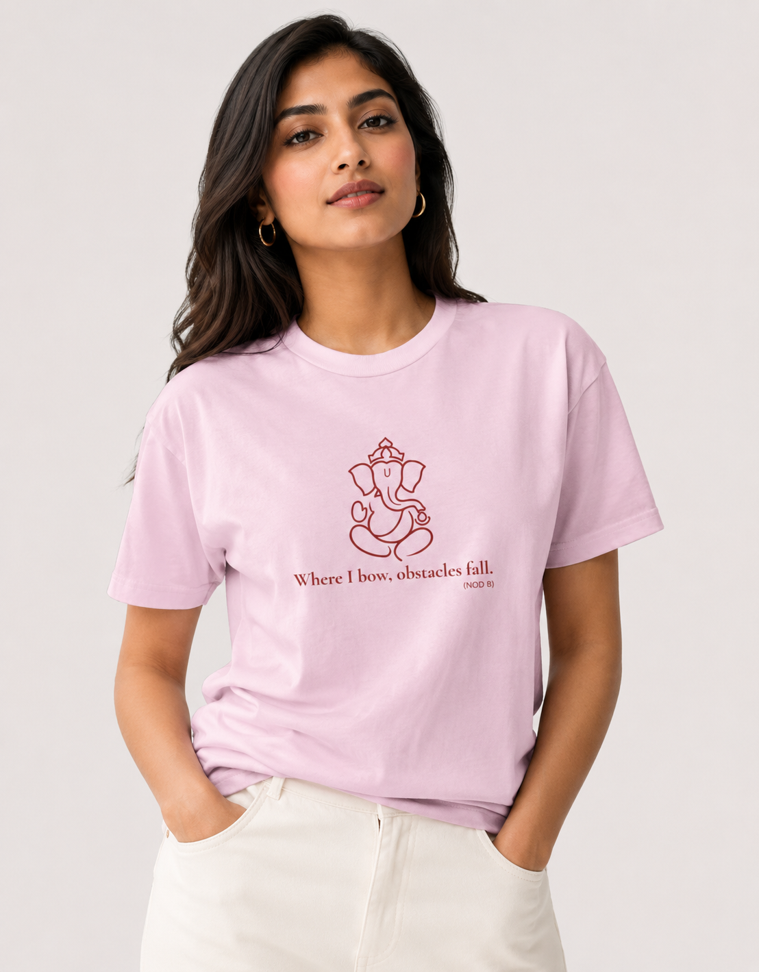 Woman modeling a light baby pink unisex cotton t-shirt with a red Lord Ganapati design by Vedic Bridge.